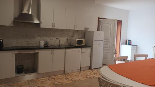 a kitchen with white cabinets and a white refrigerator at Pousada starlite in Regilde