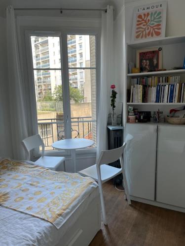 une chambre avec un lit, une table et une fenêtre dans l'établissement Joli appartement près de Montmartre, à Paris