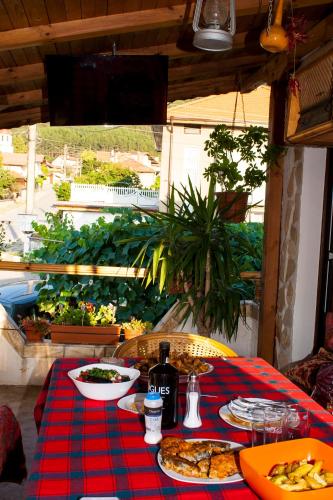 a table with a red and blue checkered table cloth with pizza at Къща за гости Ози in Ovchartsi