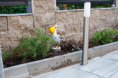 a bird with a yellow bowl on its head standing in a garden at Къща за гости Ози in Ovchartsi