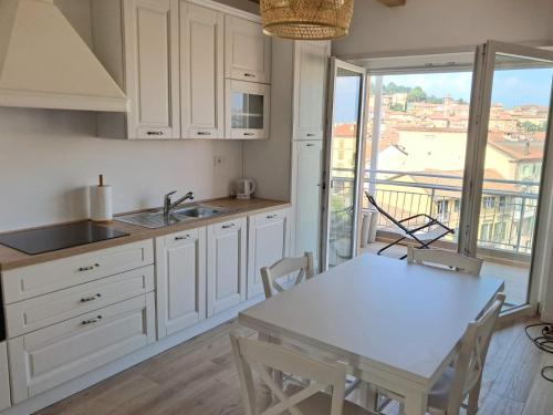 a kitchen with white cabinets and a table and a view at Attico Saluzzo centro 2 in Saluzzo