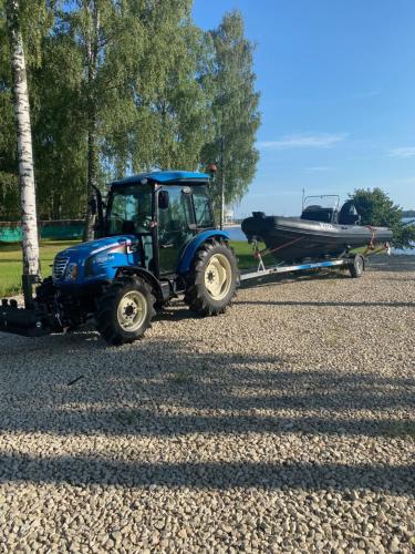 a tractor pulling a boat on a trailer at Daugava in Aizkraukle
