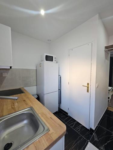 une cuisine avec un évier et un réfrigérateur blanc dans l'établissement Appartement 10 min de stade de France et 15 min de airport CDG, à La Courneuve
