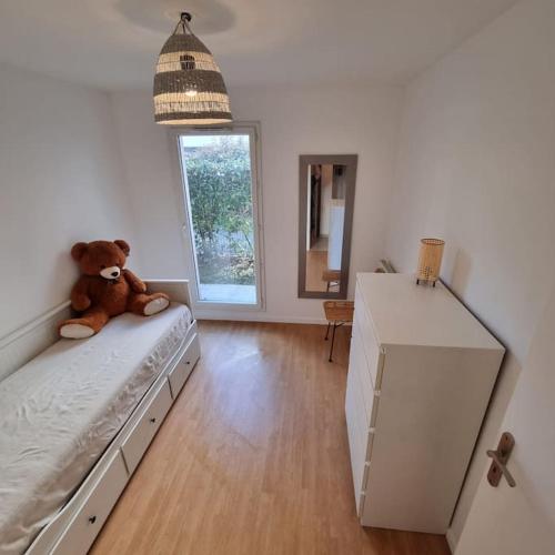 - un ours en peluche assis sur un lit dans une pièce dans l'établissement Appartement F3 Vaires-sur-Marne, à Vaires-sur-Marne