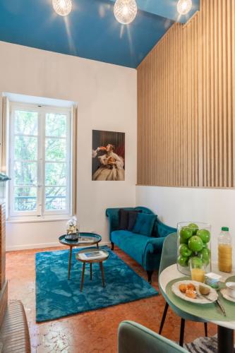 Elle comprend un salon doté de plafonds bleus et d'un canapé bleu. dans l'établissement T2 Climatisé de charme, pour couple proche Arènes MaisonCarréeConciergerie, à Nîmes