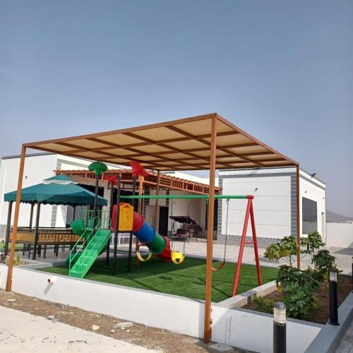 a playground with a canopy and a swing at استراحة العز in Mu‘tamar