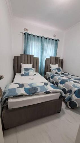 two beds sitting next to each other in a bedroom at Emat Guesthouse in Lilongwe