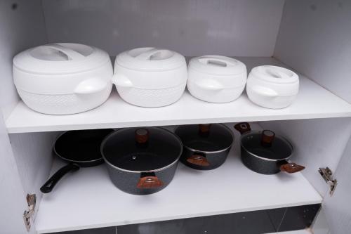 a row of white pots and pans on a shelf at Emat Guesthouse in Lilongwe