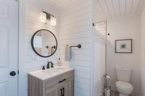 Un baño blanco con lavabo y espejo. en Charming 1960s Cottage, 5 Min Walk to Beach and Shops, en Oak Island