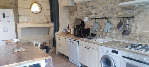 une cuisine avec un lave-linge et un mur en pierre dans l'établissement Maison avec vue sur vignes proche CNPE, à Saint-Genès-de-Blaye