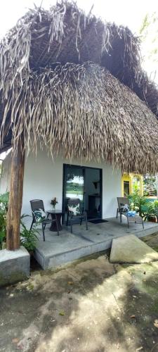 a large straw hut with two chairs and a table at Chagres River Lodge in Santa Rosa