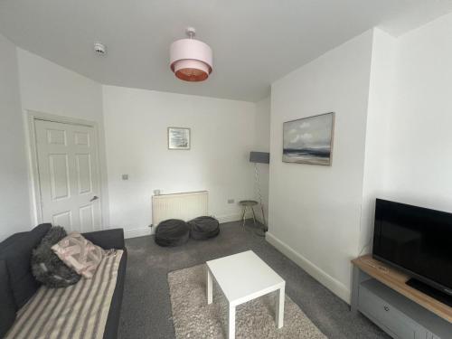 a living room with a couch and a tv and a table at New Flat in Lytham St Annes - Sleeps 4 in Saint Annes on the Sea