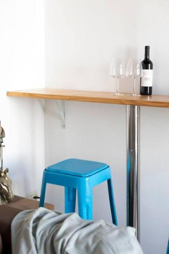 a blue stool sitting under a shelf with a bottle of wine at Cozy Tiny House in Neve Tzedek, 3m walk to Beach! in Tel Aviv