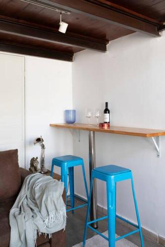 two blue stools in a room with a bar at Cozy Tiny House in Neve Tzedek, 3m walk to Beach! in Tel Aviv