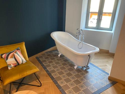 - une baignoire blanche dans une chambre avec une chaise dans l'établissement La Bohème, Maison de bourg, à Chaudes-Aigues