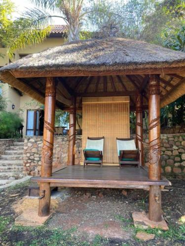 a wooden gazebo with two chairs on it at Bali at Scenic Haven Lodge in Hartbeespoort in Hartbeespoort