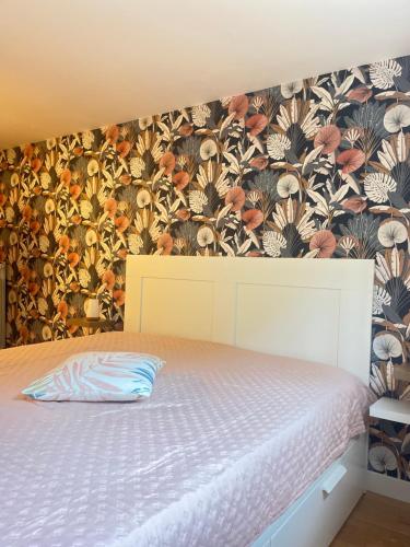 une chambre avec un lit avec un papier peint fleuri dans l'établissement Logement près de Disneyland Paris, à Pontault-Combault