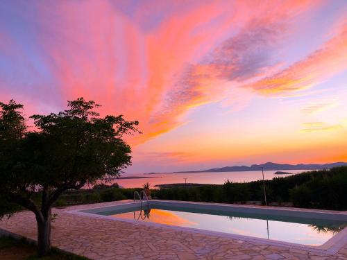 a swimming pool with a sunset in the background at Paros Afrodite Luxury Villas in Aliki