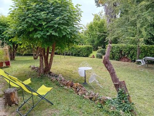 un jardin avec des chaises, une table et un arbre dans l'établissement Petite maison avec jardin, à Montcaret