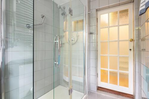 a shower with a glass door in a bathroom at Ultra Central London, Garden, King Bed in London