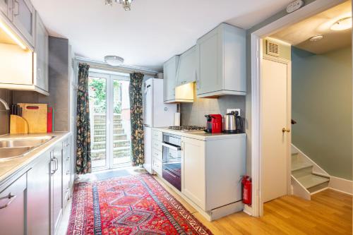 a kitchen with white cabinets and a red rug at Ultra Central London, Garden, King Bed in London