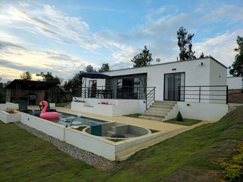 a house with a pool with a pink duck in it at Villa moderna con una hermosa piscina, fogata y BBQ in Los Santos