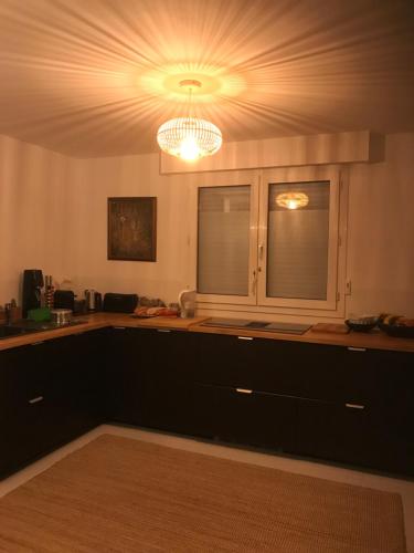 une cuisine avec des placards noirs et un lustre dans l'établissement A l orée du lac Moriscot, chouette T3, idéale famille ,4 à 6 personnes, très bien desservie, à Biarritz