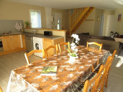une table de salle à manger avec des chaises et une cuisine dans l'établissement Gîte de la chouette, à Hattenville