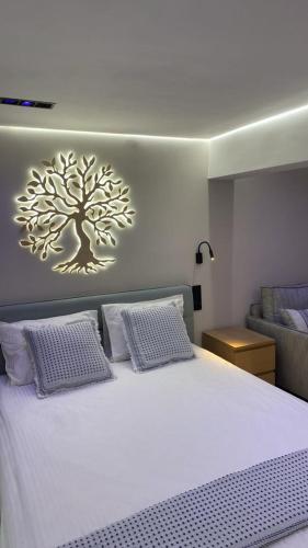 a bedroom with a white bed with a tree on the wall at Elements of Diros in Pirgos Dhirou