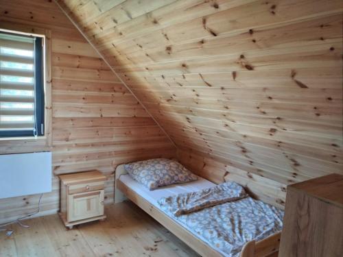 a bed in a room with a wooden wall at Domek Arkadia in Gąski