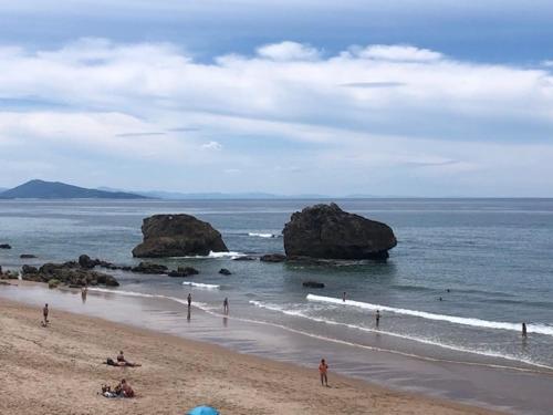 un groupe de personnes sur une plage avec des rochers dans l'eau dans l'établissement A l orée du lac Moriscot, chouette T3, idéale famille ,4 à 6 personnes, très bien desservie, à Biarritz