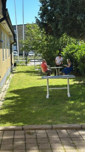 three people sitting on a bench in a park at Hotell Lamar in Ängelholm
