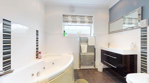 a white bathroom with a tub and a sink at Sleeps 10, Free parking, close to Science Park, King size bed in Milton