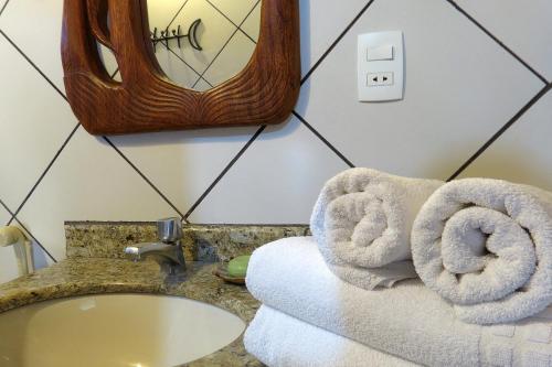 a bathroom with towels and a sink and a mirror at Chalé do Bosque in Bonito