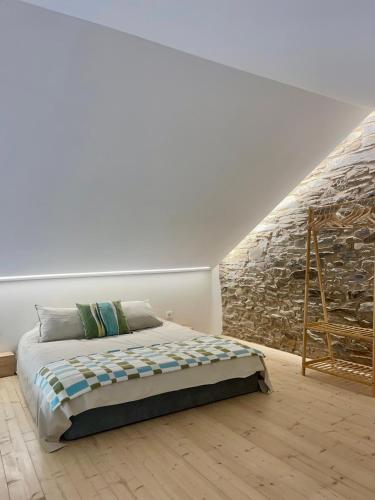 a bedroom with a bed and a stone wall at Turismo e Alojamento dos Lagos do Sabor - Piscina & SPA in Meirinhos