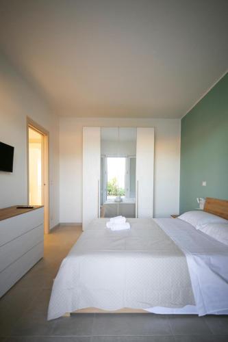 a bedroom with a large white bed and a television at Dimore degli Ulivi in Leporano
