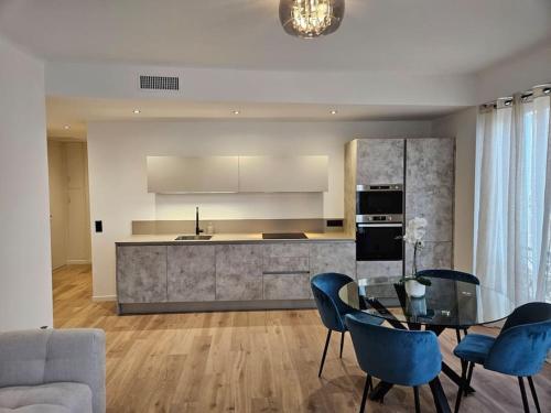 une cuisine avec une table en verre et des chaises bleues dans l'établissement Très bel appartement Nice centre, à Nice