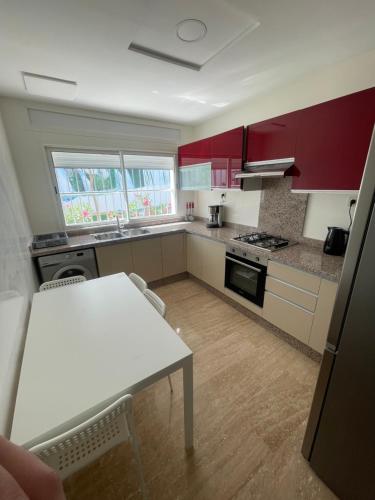 a kitchen with red cabinets and a white table at Bab diki Appart 1 in Ksar es Sghir