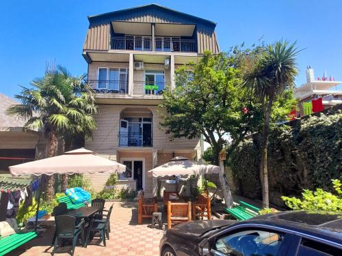 a building with tables and umbrellas in front of it at Guest House Deme in K'obulet'i