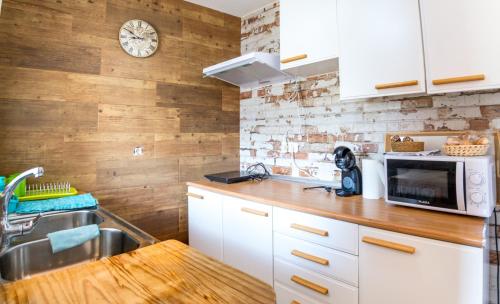 a kitchen with white cabinets and a clock on the wall at Loft Medieval Del Júcar in Alcalá del Júcar