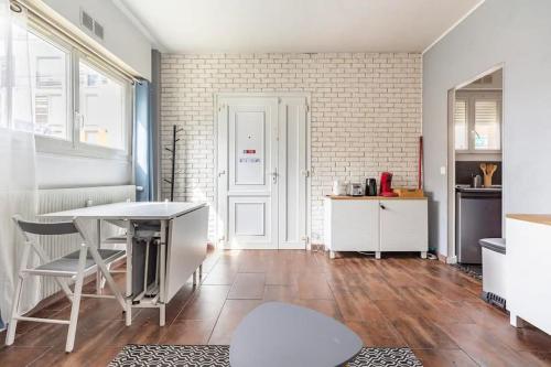 une cuisine avec une table et des chaises ainsi qu'un mur en briques dans l'établissement Appartement F2 Villeparisis, à Villeparisis