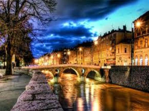 a bridge over a river in a city at night at Old Town Hotel in Sarajevo