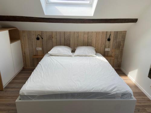 a bedroom with a bed with white sheets and a window at Duplex in Waimes