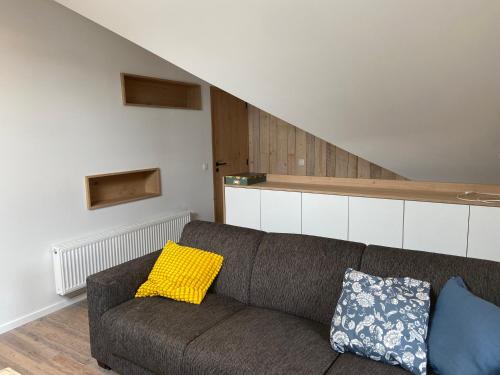 a living room with a couch with yellow and blue pillows at Duplex in Waimes