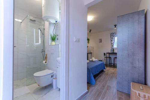 a bathroom with a toilet and a shower and a bed at Cozy stone house close to the beach in Kaštela