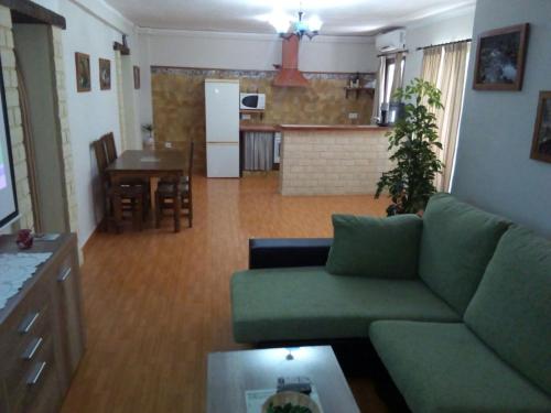 a living room with a green couch and a kitchen at Casa Rural Majaceite in El Bosque