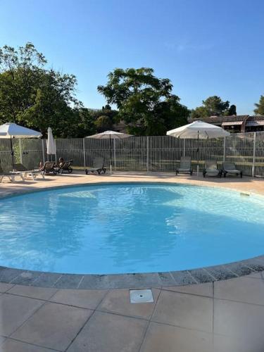 une grande piscine bleue avec chaises et parasols dans l'établissement Charmante maison provençale, à Grasse