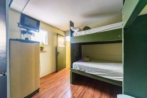 a room with two bunk beds and a flat screen tv at Hostel Multiverso in Santo André