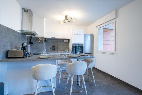 une cuisine avec tabourets blancs et comptoir dans l'établissement Spacieux - 4 pers' - Balcon - 2 lits - Parking, à Woippy