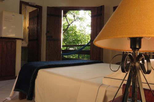 a bedroom with a bed with a lamp and a window at Chalé do Bosque in Bonito